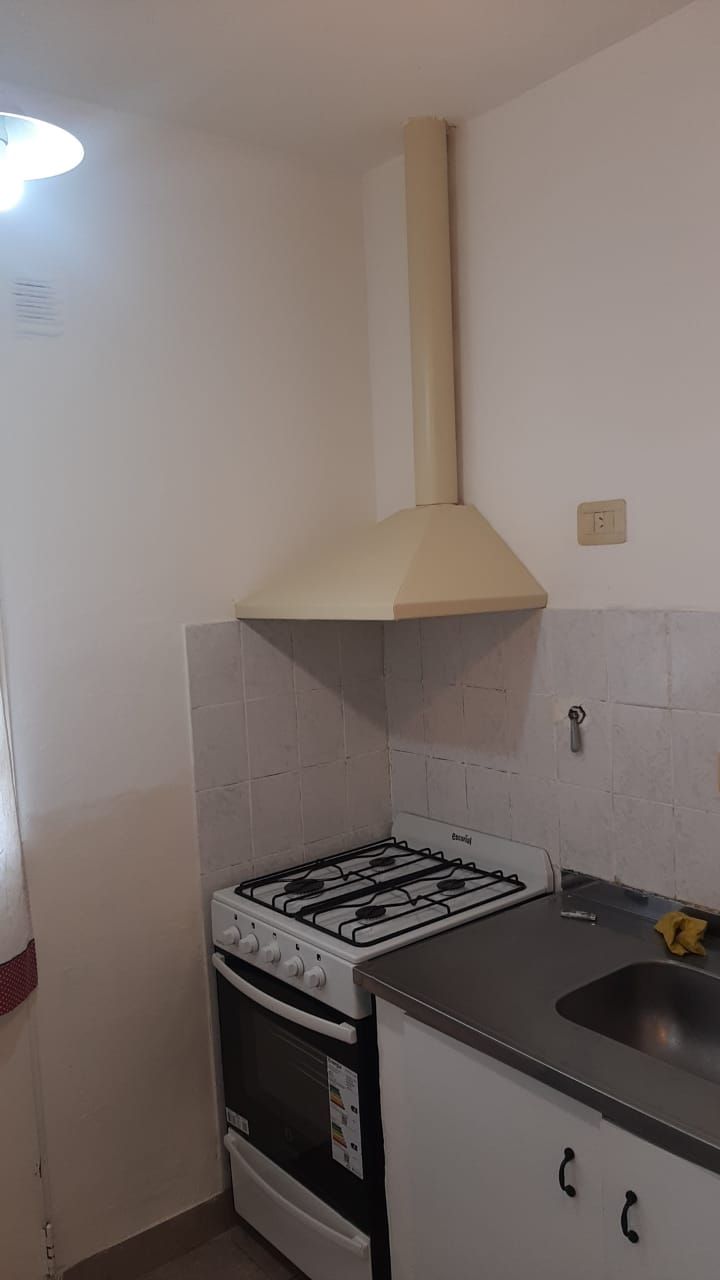 Cocina con cocina a gas, campana y mesada de acero.