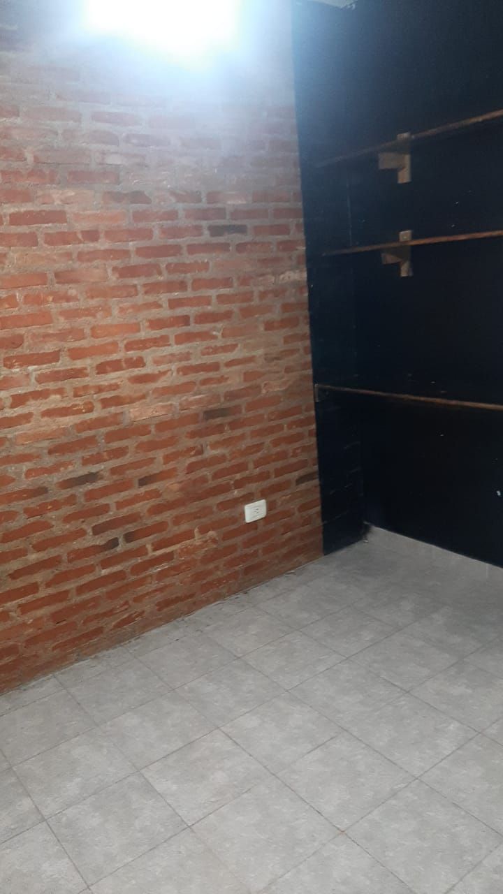 Ladrillo visto junto a una pared oscura con estantes.