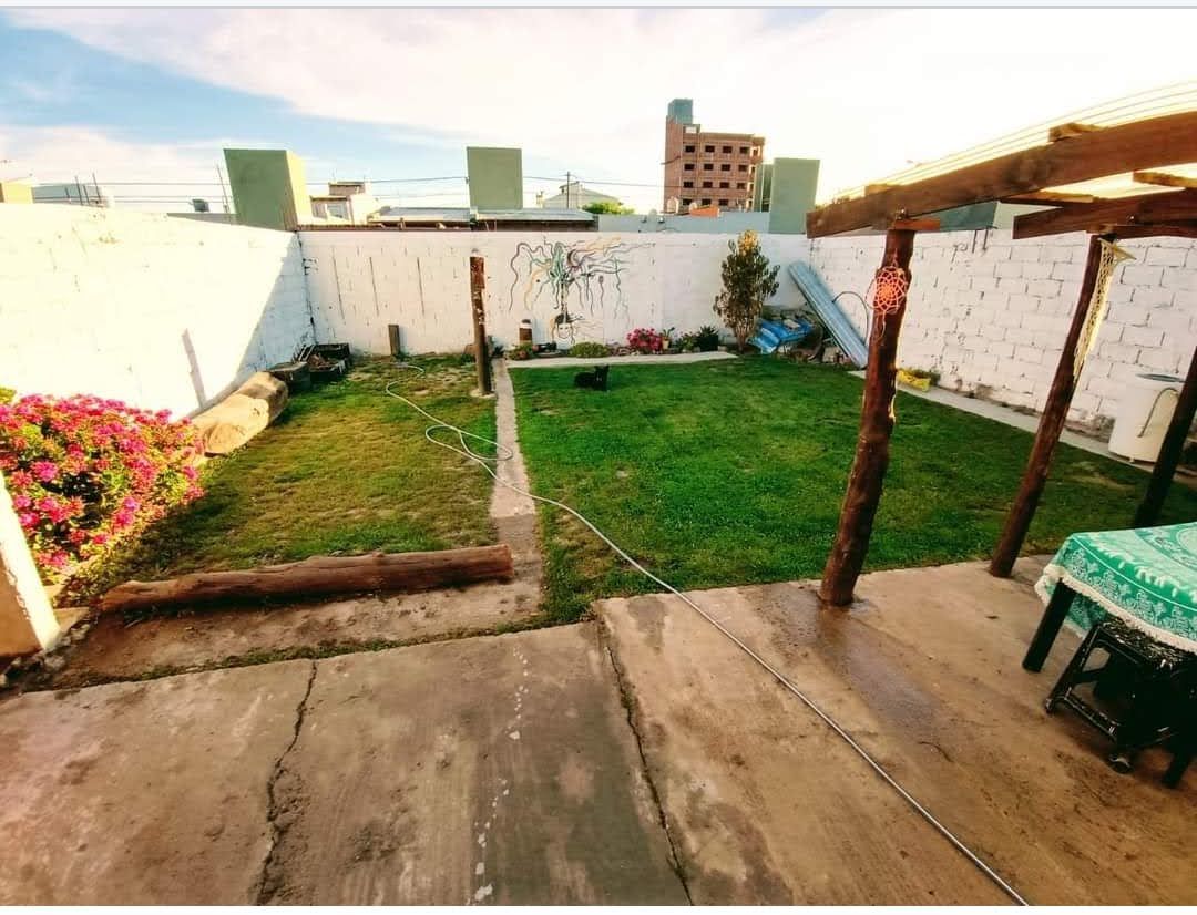 Patio con césped y deck de madera bajo la pérgola.