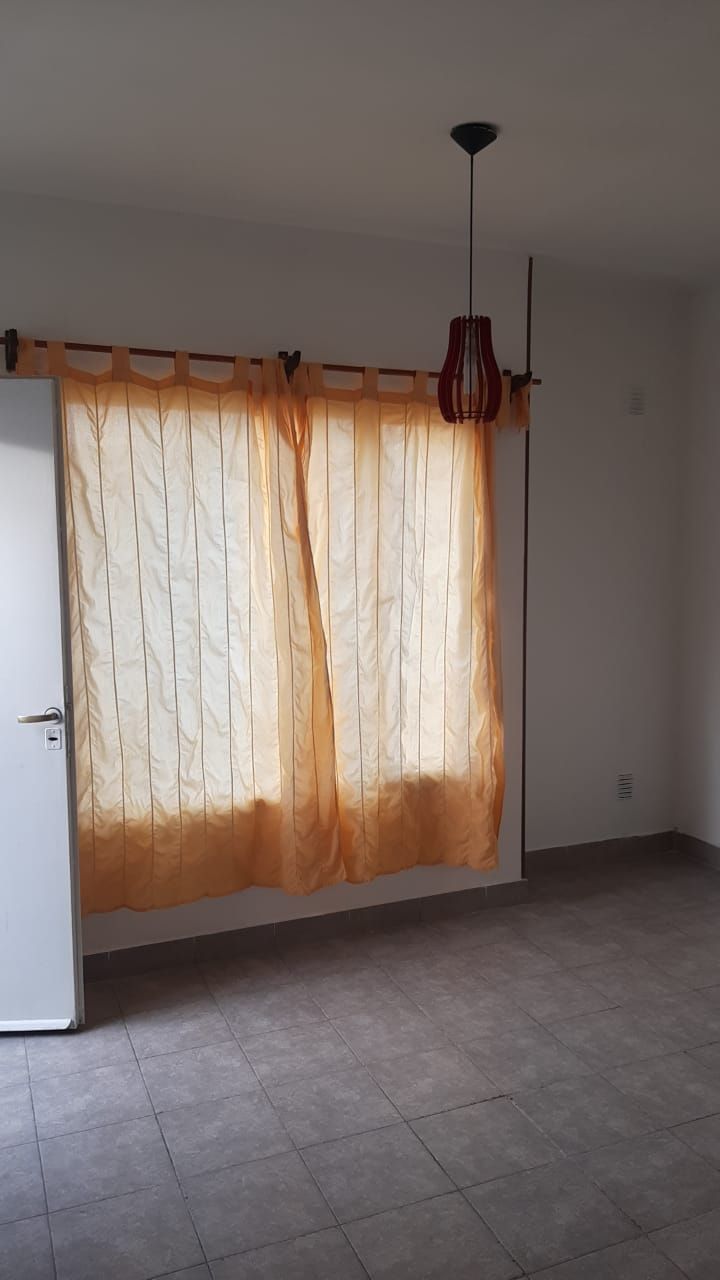 Ambiente con ventana y cortina de tela naranja.